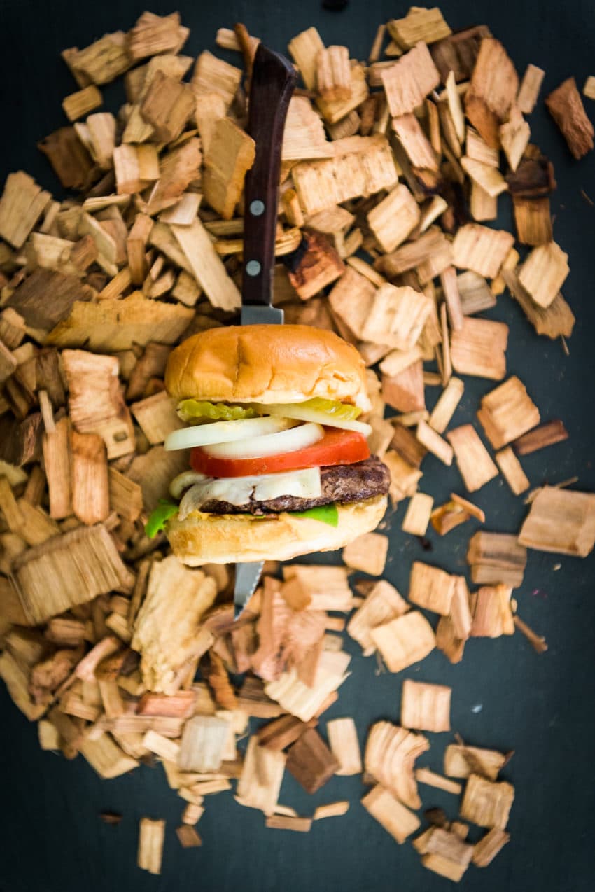 Burger on a board with wood chips.