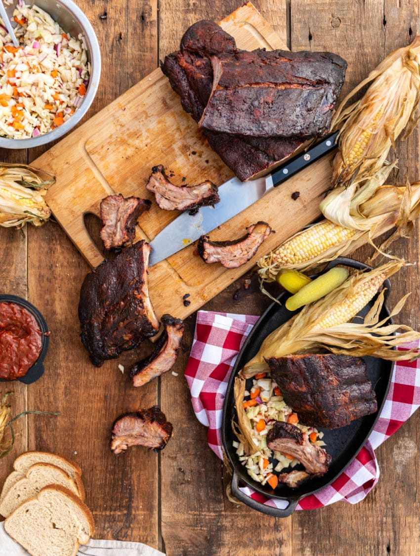 Overhead image showing smoked ribs on cutting board, being cut into individual ribs for serving. 