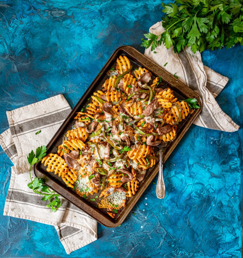 loaded cheesesteak fries on a platter. recipe from girlcarnivore.com