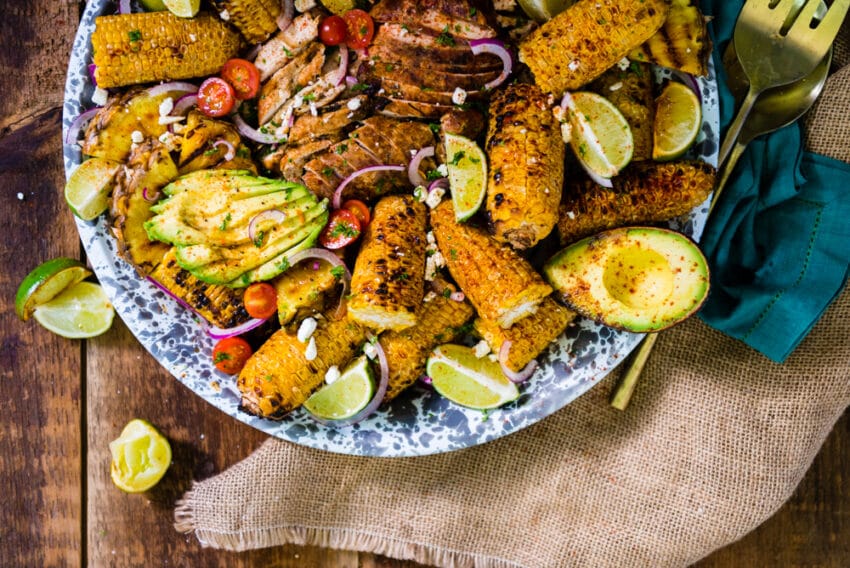 A platter of vibrant smoked chicken avocados and vegetables. 