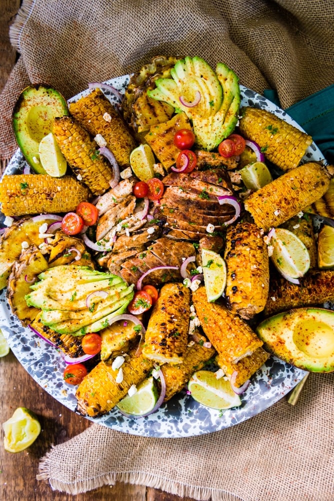 Sliced smoked chicken breast with grilled corn on giant platter.