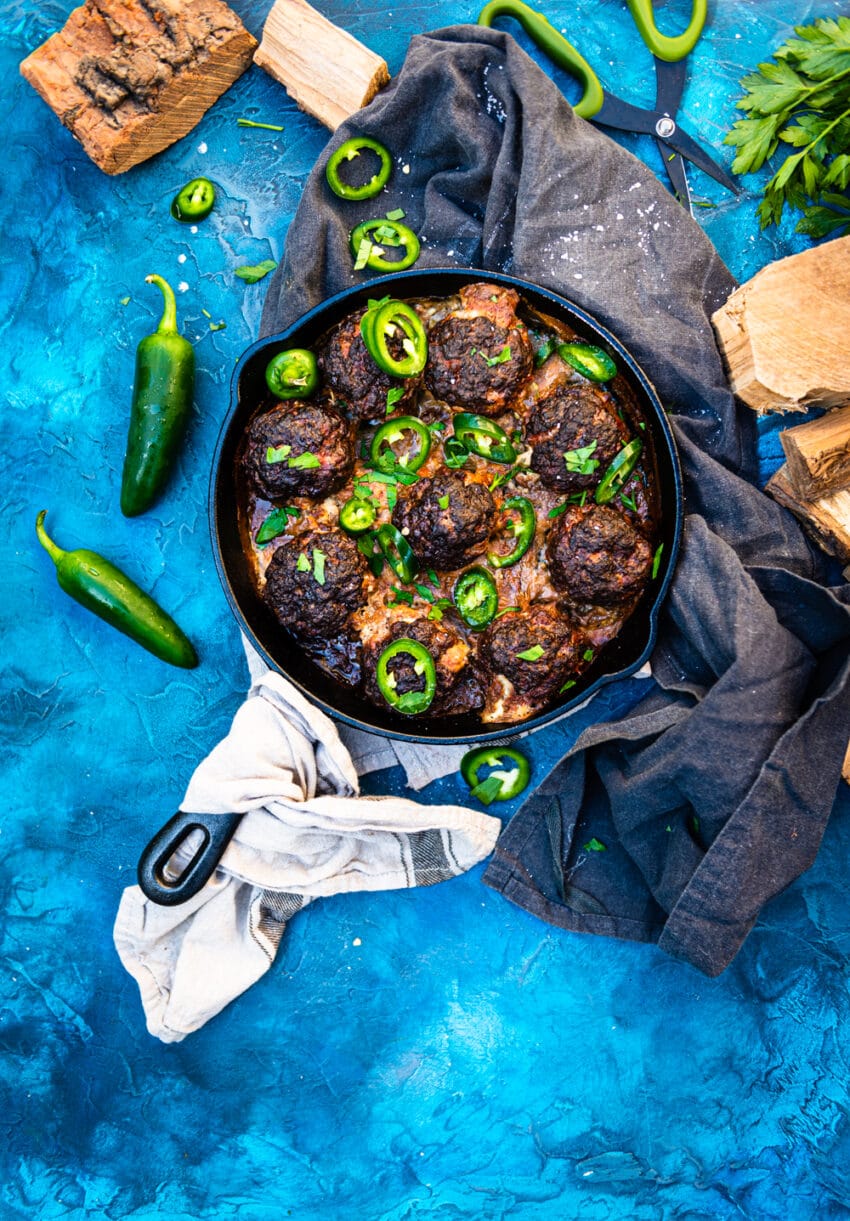 skillet filled with smoked jalapeno popper meatballs and sliced fresh jalapeno