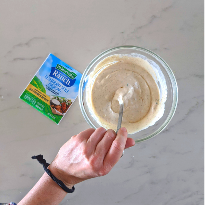 hand mixing hidden valley ranch dressing in bowl