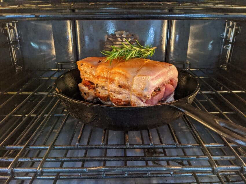 Pork roast stuffed, rolled and in oven to cook.