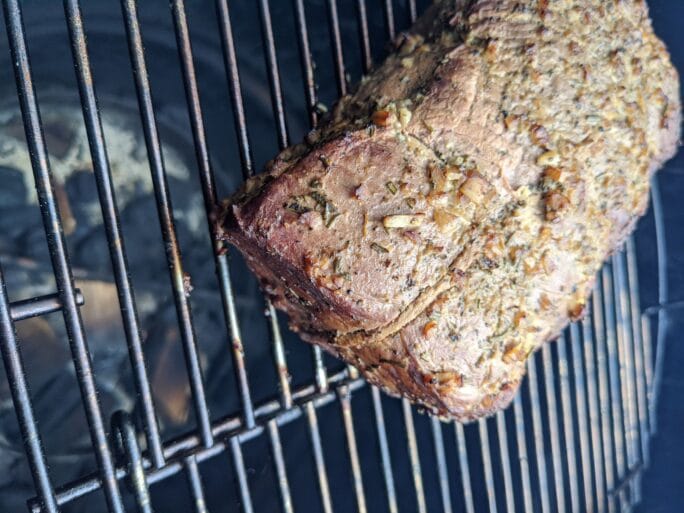 herb and garlic rubbed roast over coals in a smoker