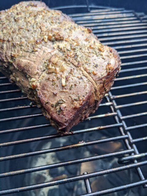 herb and garlic rubbed roast over coals in a smoker
