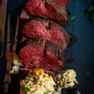 A smoked tenderloin is sliced and garnished with arugula.