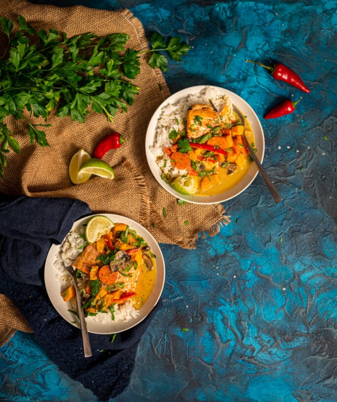 above shot of two bowls of comforting salmon curry with veggies over rice