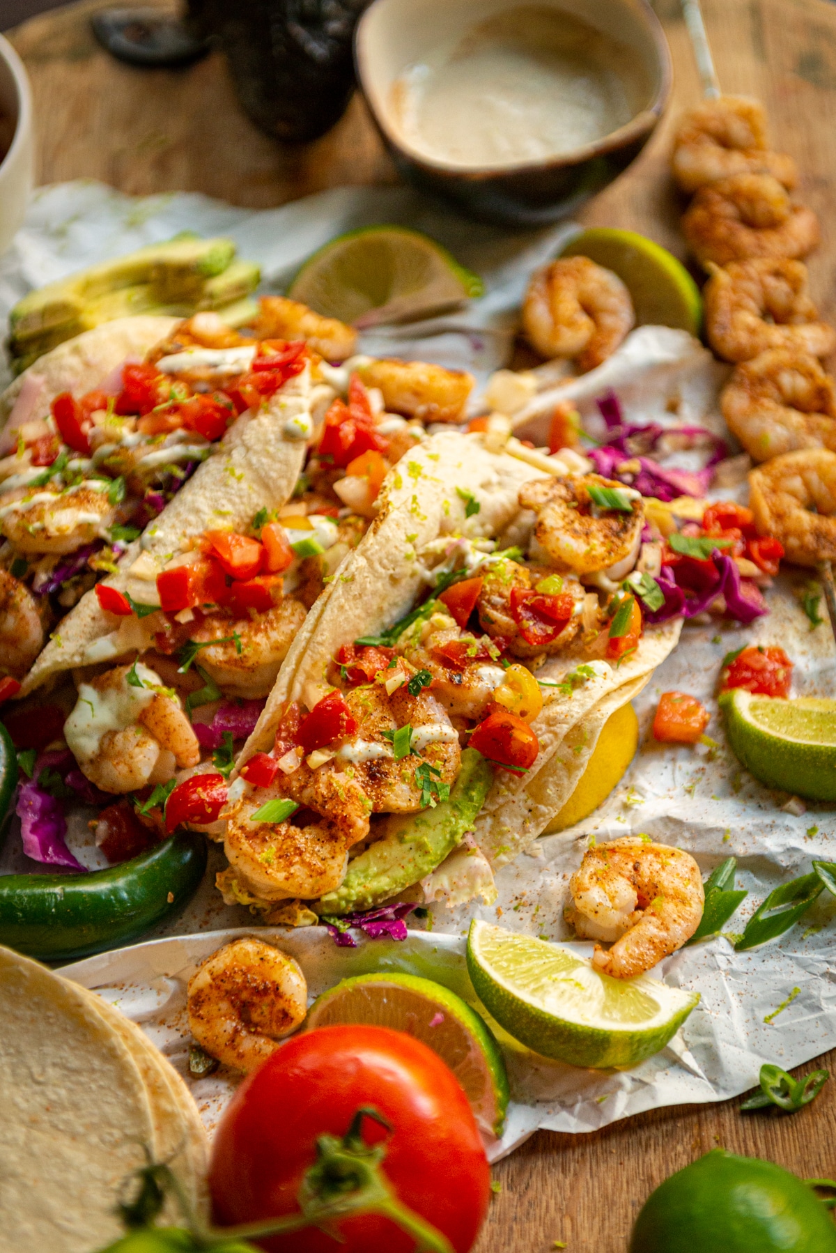 Cajun rubbed grilled shrimp tacos in tortillas with red and green cabbage slaw, a drizzle of crema, pico de gallo and limes around to squeeze on top