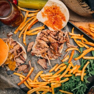 pulled pork sandwiches shown with vinegar sauce and one with mustard sauce from the top on a platter with fries