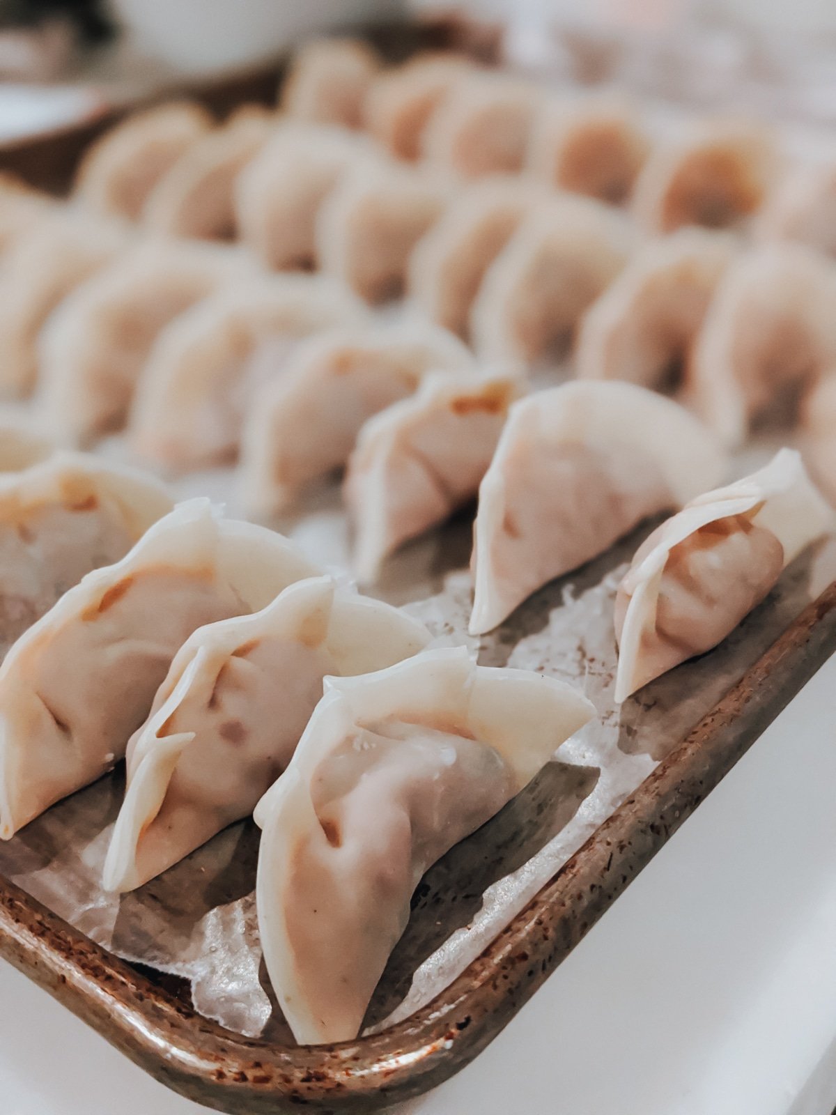 dumplings made, lined up in rows on a baking sheet, and ready for the freezer