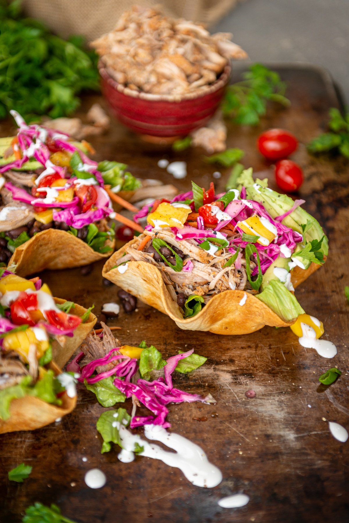 brightly colored and fresh - 3 fried tostada bowls filled with shredded carnitas, veggies, mangoes, pickled cabbage and crema 