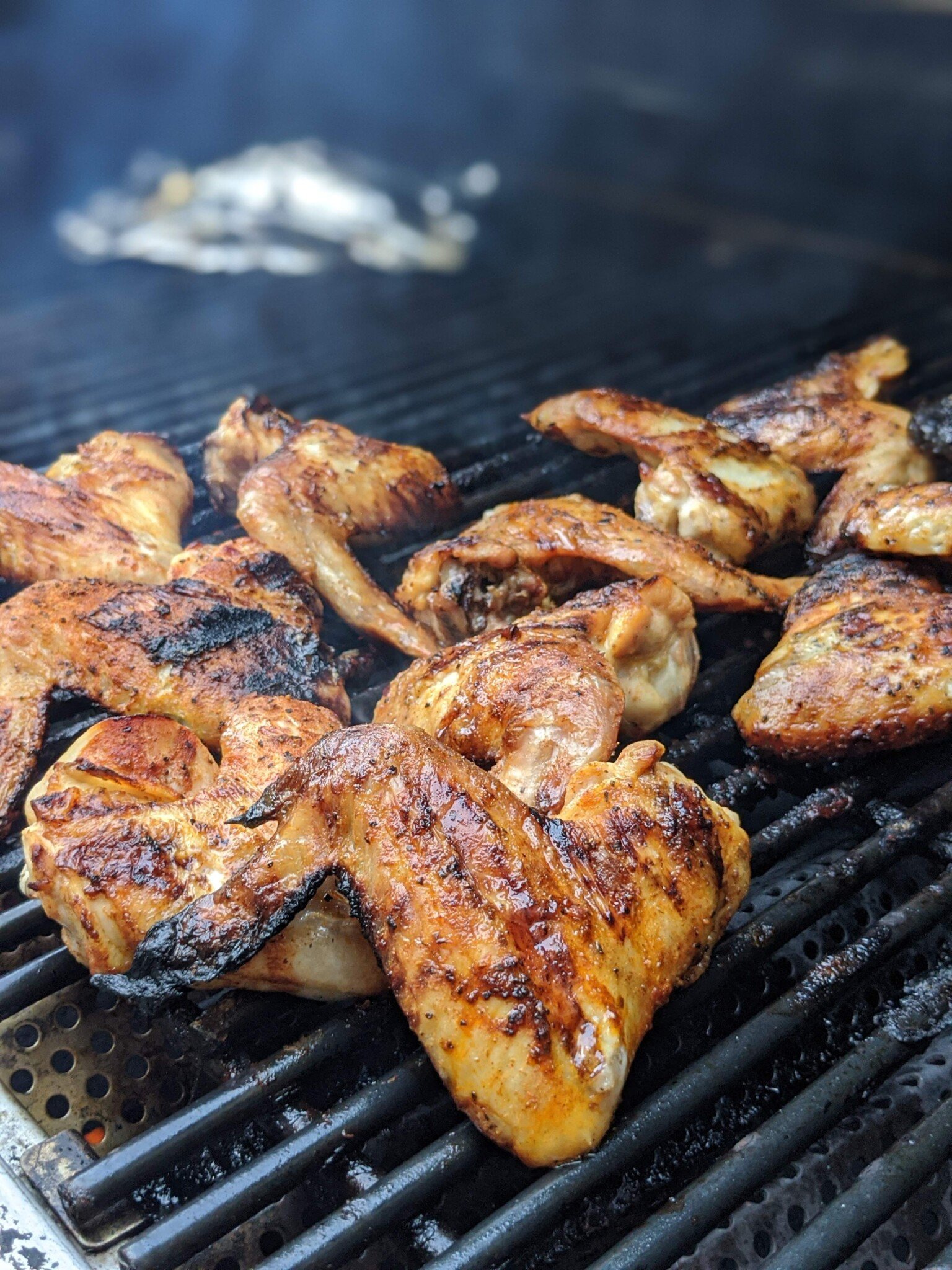 Chicken wings on Viking gas grill with foil wood chip packet in background. 