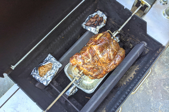 Above shot of gas grill used as rotisserie with wood chip packets in foil and rib roast 