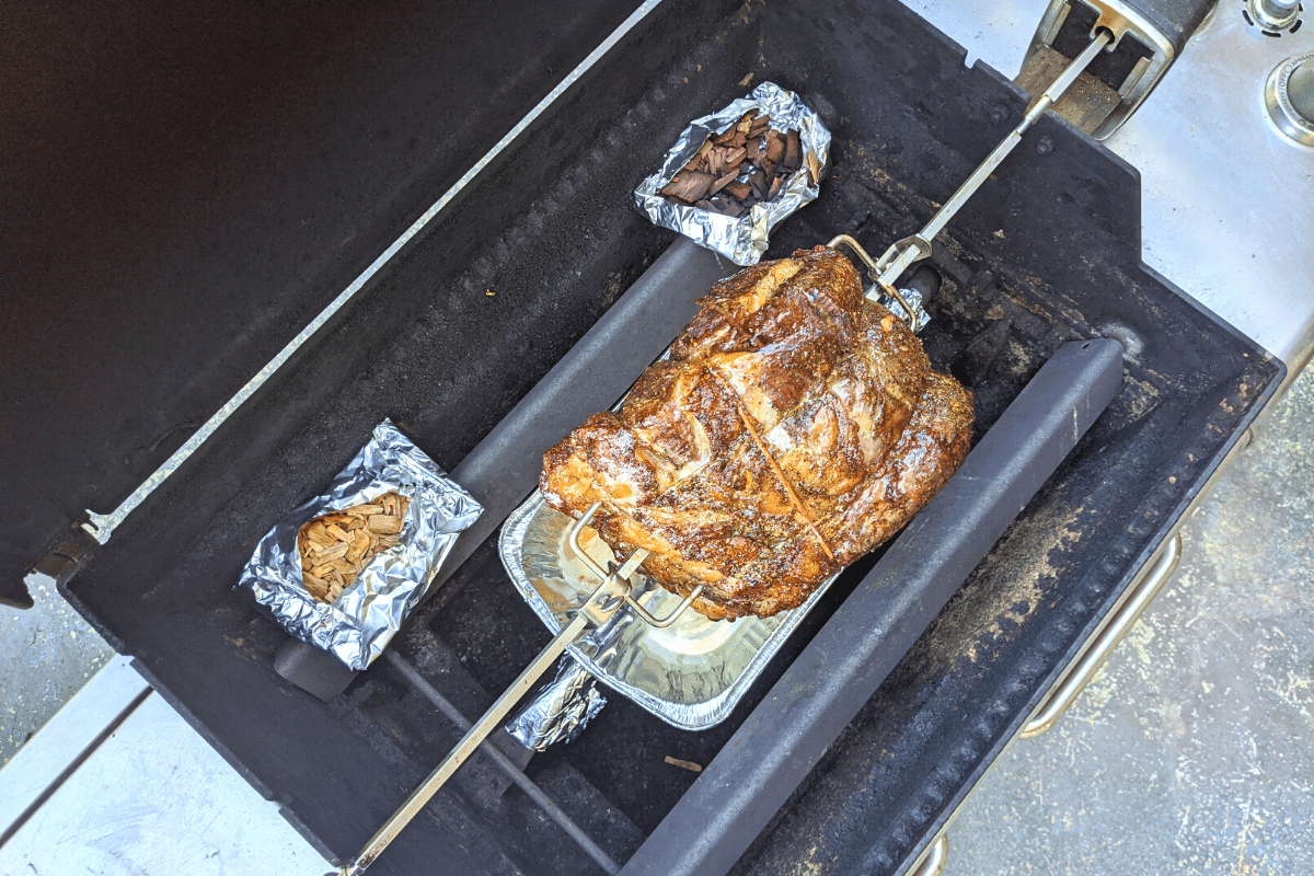 Above shot of gas grill used as rotisserie with wood chip packets in foil and rib roast. 