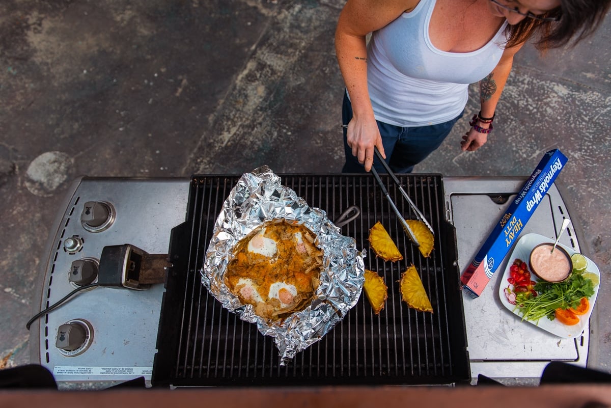 above shot of Kita grilling chilaquiles on a gas grill with pineapple slices 