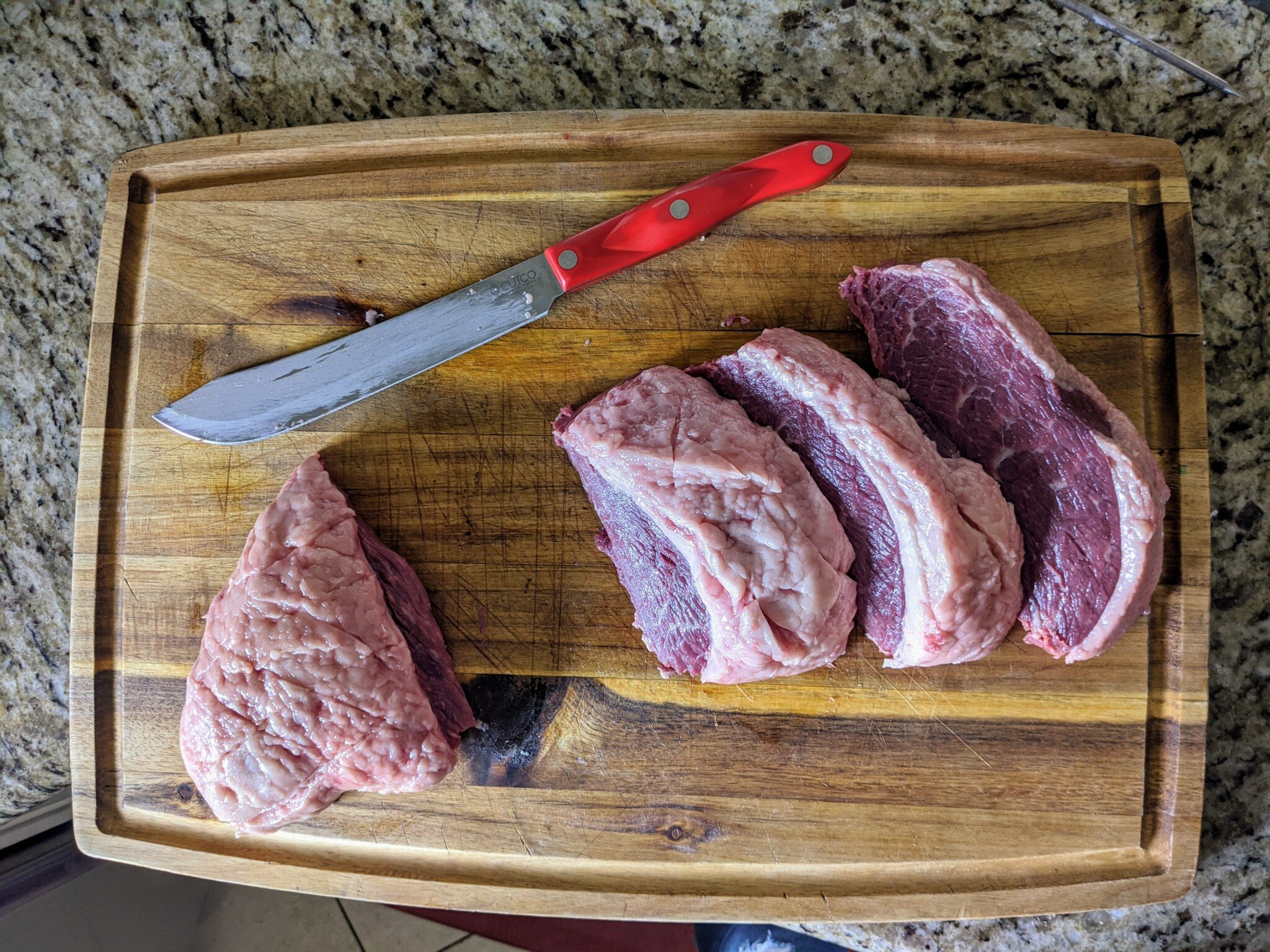 Thick cuts of picahna ready to be skewered on cutting board with knife. 