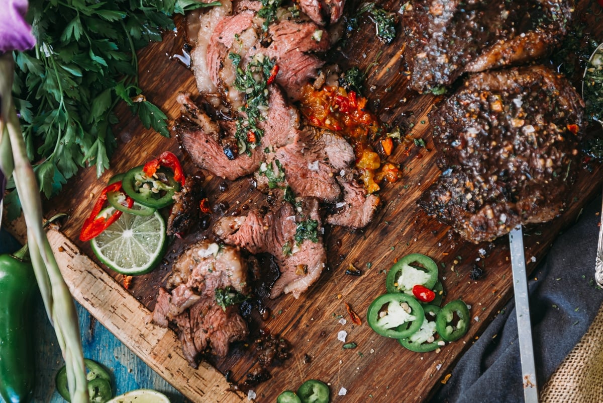 Sliced picanha on a cutting board with sliced peppers.