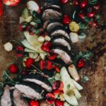 Close up of pork tenderloin with bright cherries and avocado slices