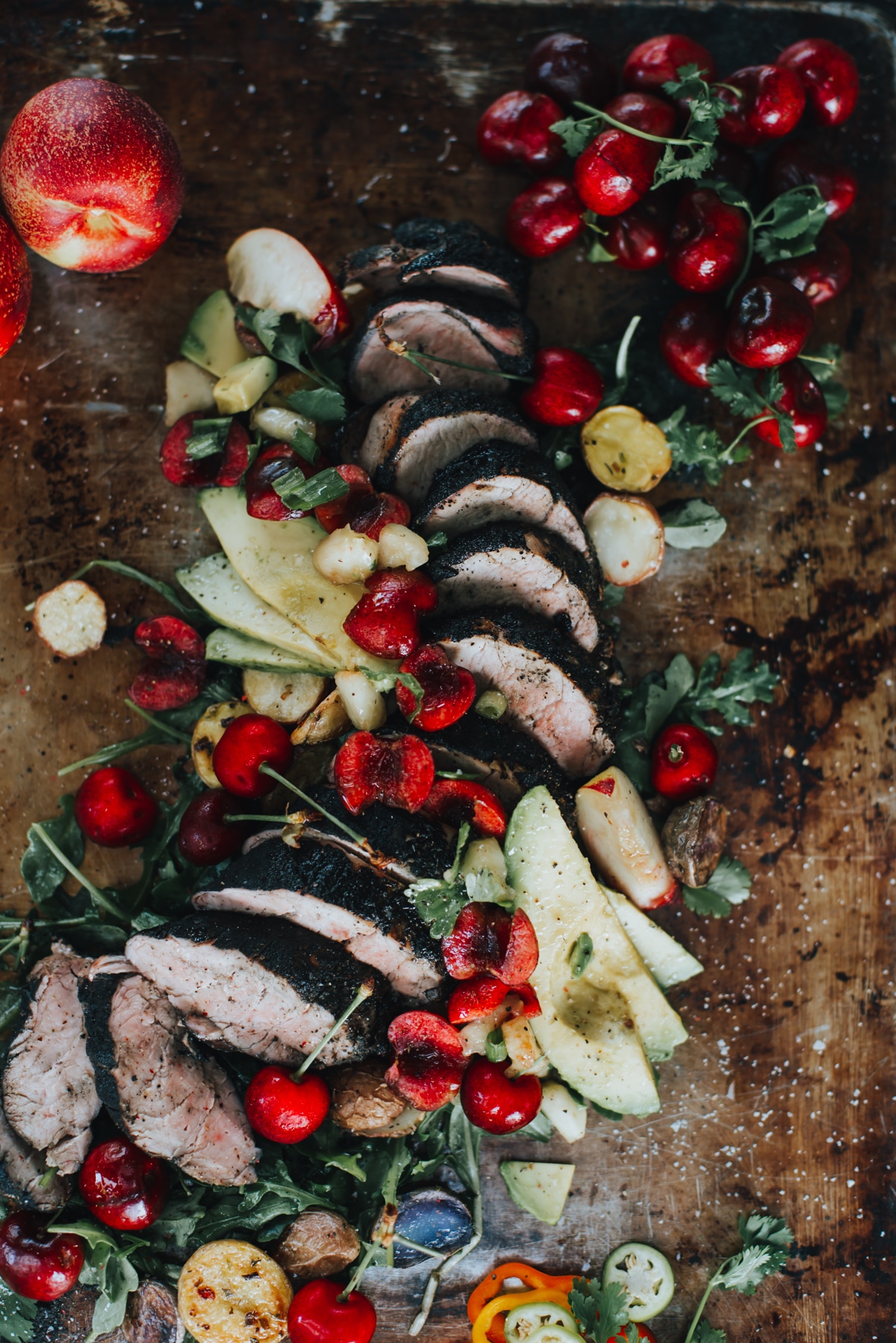 Close up of pork tenderloin with bright cherries and avocado slices 