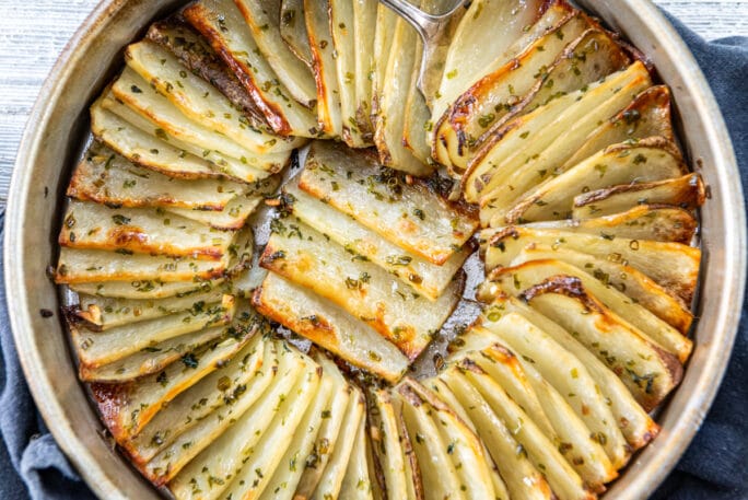 Layers of thin sliced potatoes - stacked like dominoes leaning on one another in a pan cooked til just crispy