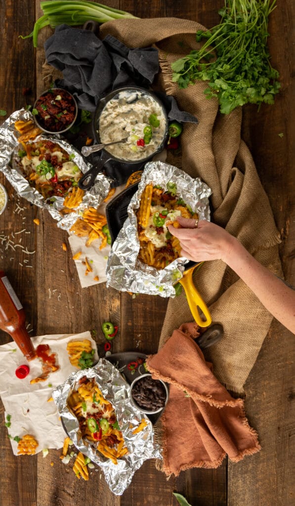 above shot of hand coming in to grab waffle fries from a messy platter of them