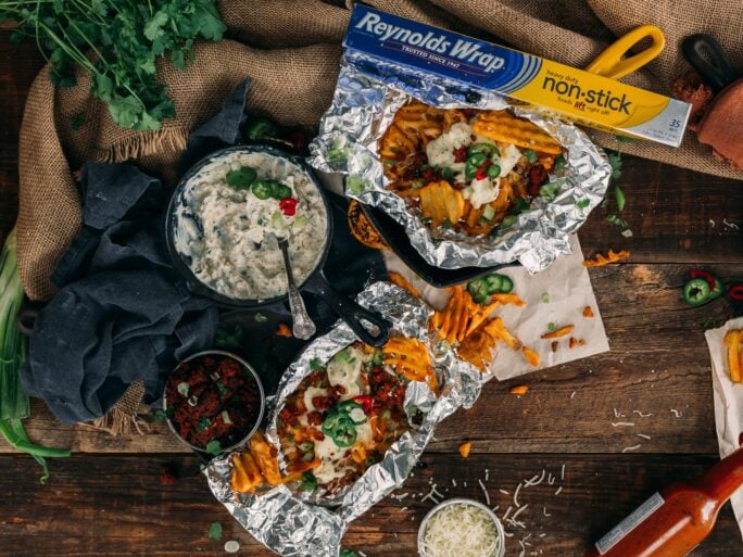 individual grilled waffle fries in foil covered in creamy jalapeno popper topping 