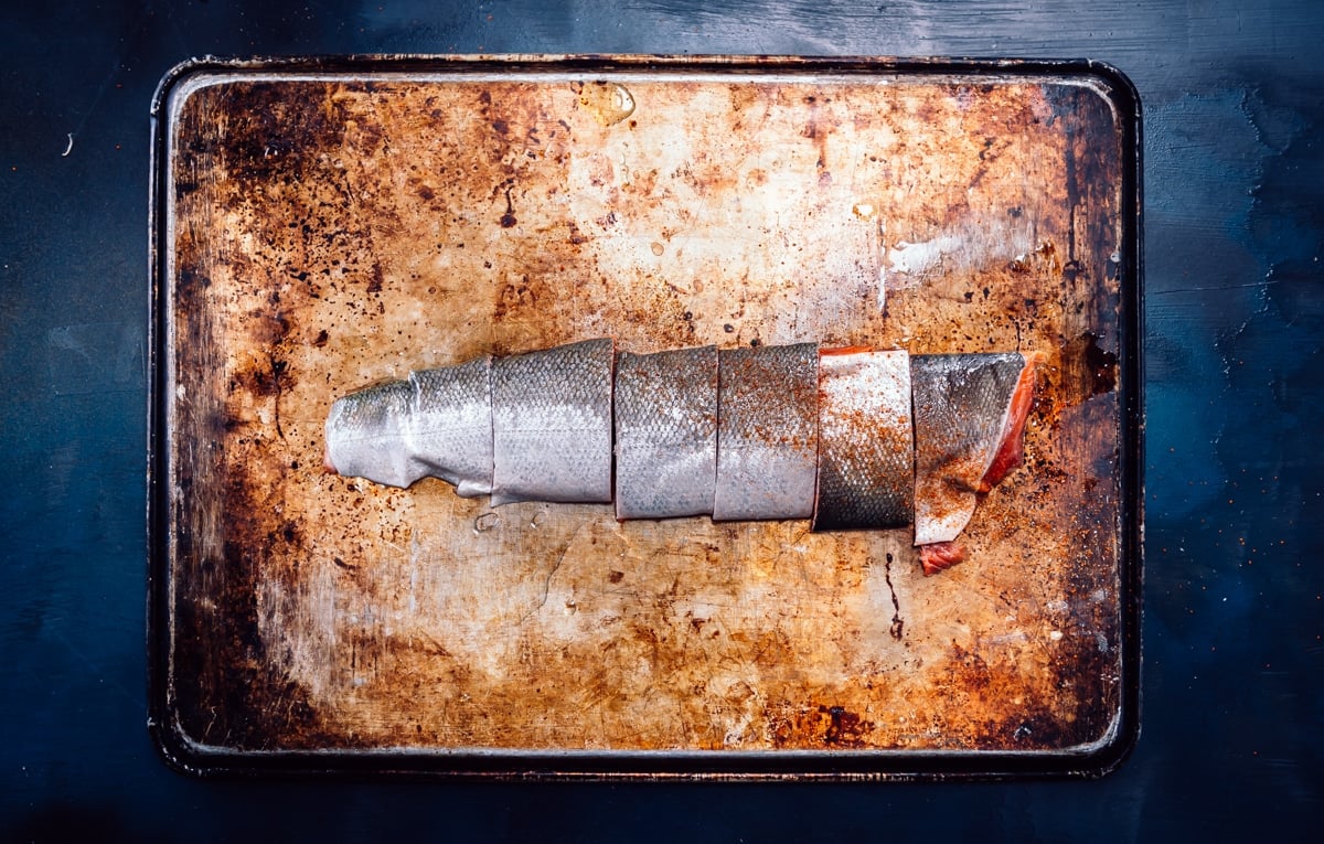 The silver skin side of the salmon filet, portioned but shown together on one board. 