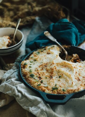 Creamy mashed potato topped shepherd's pie with Moroccan spices and a heaping portion taken out in a bowl on blue cloths