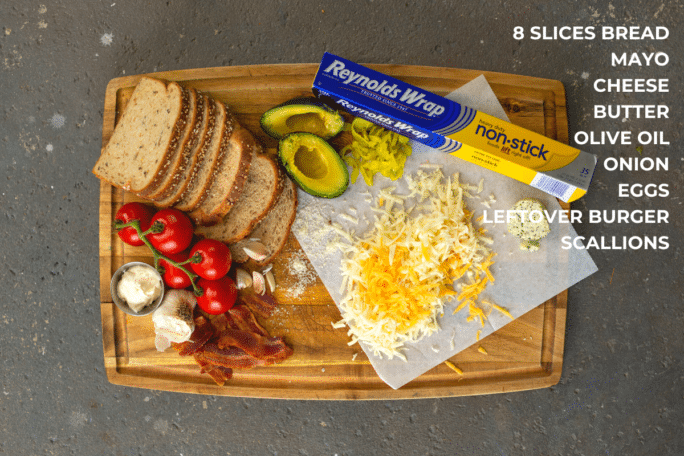 Ingredients to make the ultiamte grilled cheese, with shredded cheese, avocado, garlic, tomatoes and bread on a cutting board