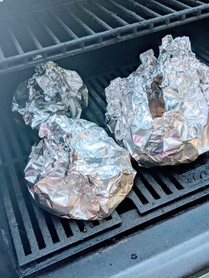 foil wrapped packets of pork bites on grill