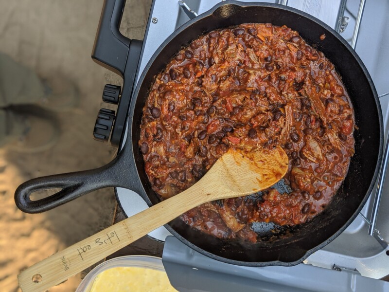 reheating pulled pork chili on camp stove in cast iron skillet