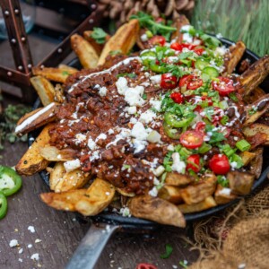 Crispy camping french fries in skillet topped with dutch oven chili
