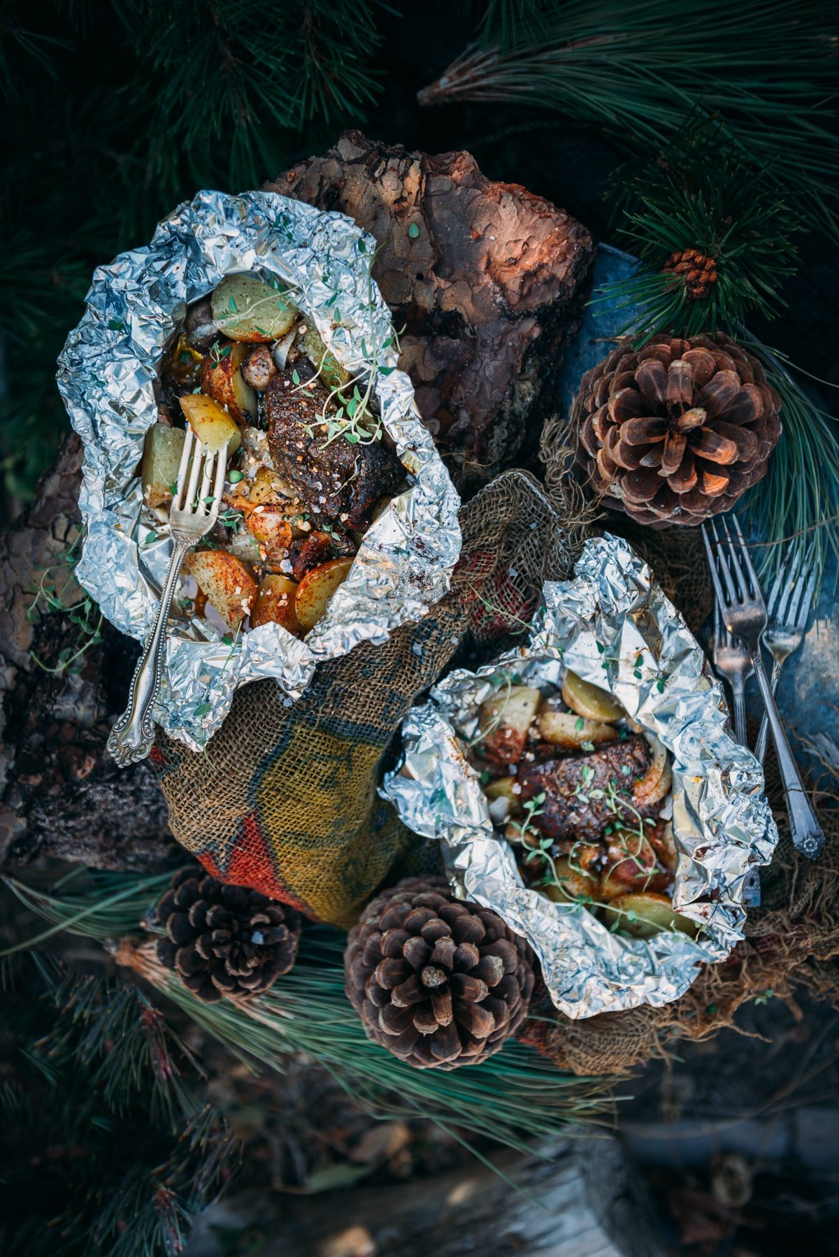 Above shot of two foil wrapped steak and potato meals opened to show food.