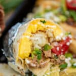 close up of make ahead burrito cooked, cut in half to show eggs, potatoes, and filling