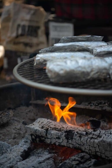 foil wrapped burritos over campfire on grill grate