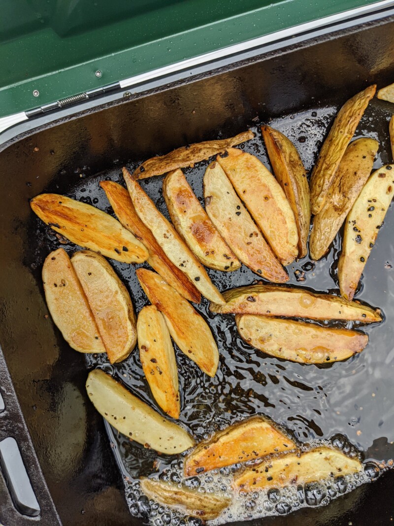 potato wedges cooking in oil on camp stove