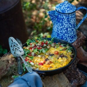 A cast iron skillet filled with frittata on a table in the woods.