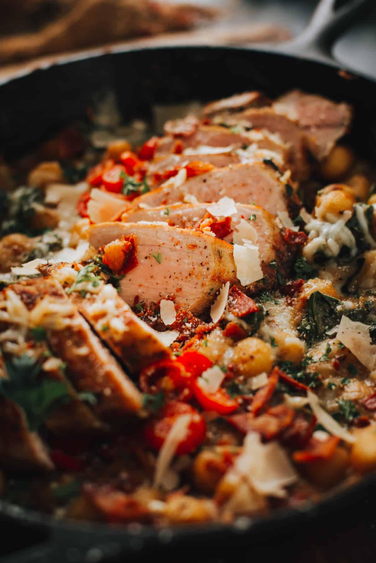 Close up of sliced pork tenderloin in skillet with gnocchi