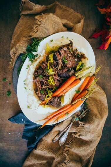 shredded mississippi pot roast on burlap served with mashed potatoes and roasted carrots