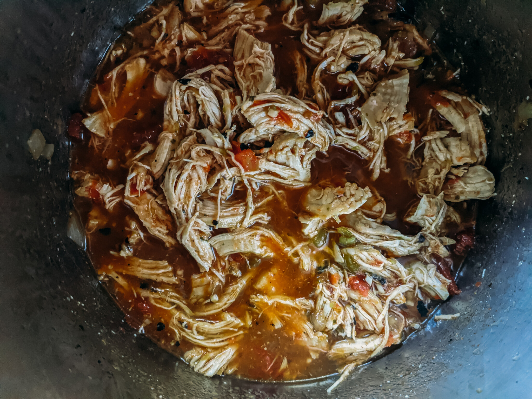 Shredded chicken in broth in a pot.