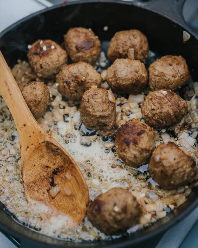 Frying Beef Meatball along with onion and spices in a Cast Iron Skillet