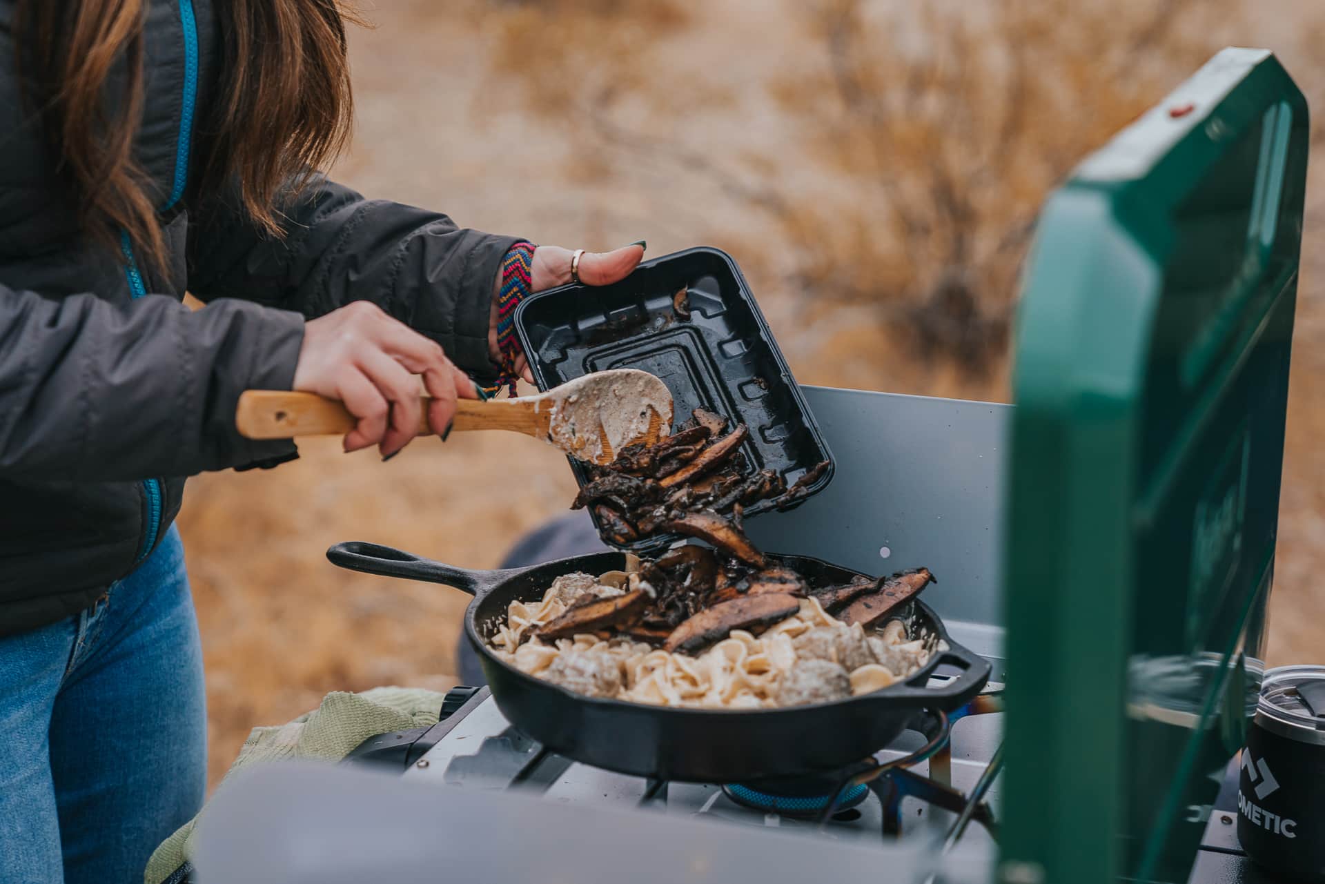 Adding mushrooms to pan - outdoor cooking on camp stove