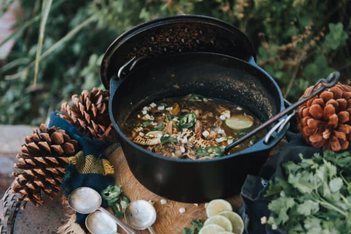 White Chicken Chili in a Dutch oven on table outside in rustic woodland setting