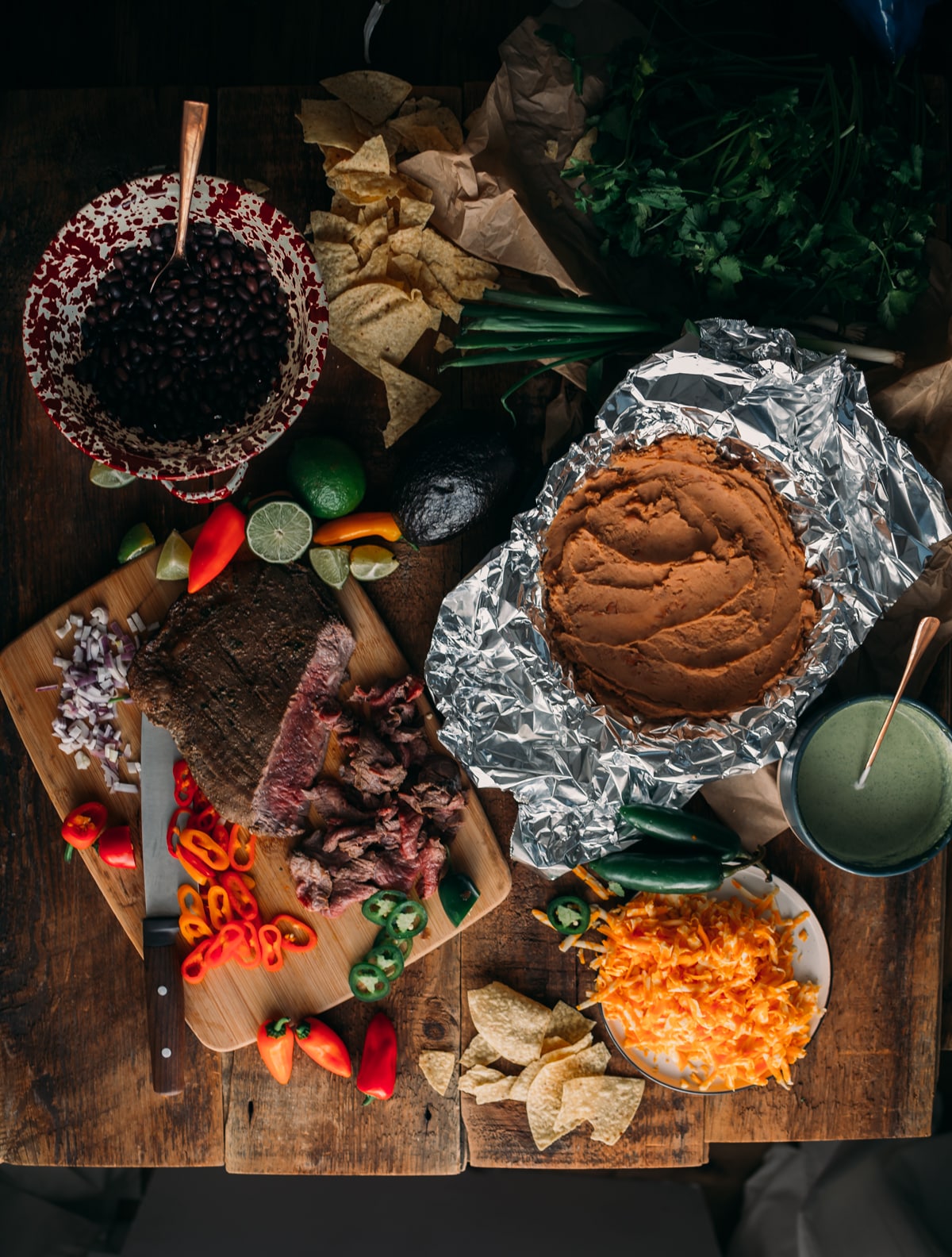 Carne Asada, tortilla chips, beans, cheese, onion and other ingredients to make Campfire Nachos.