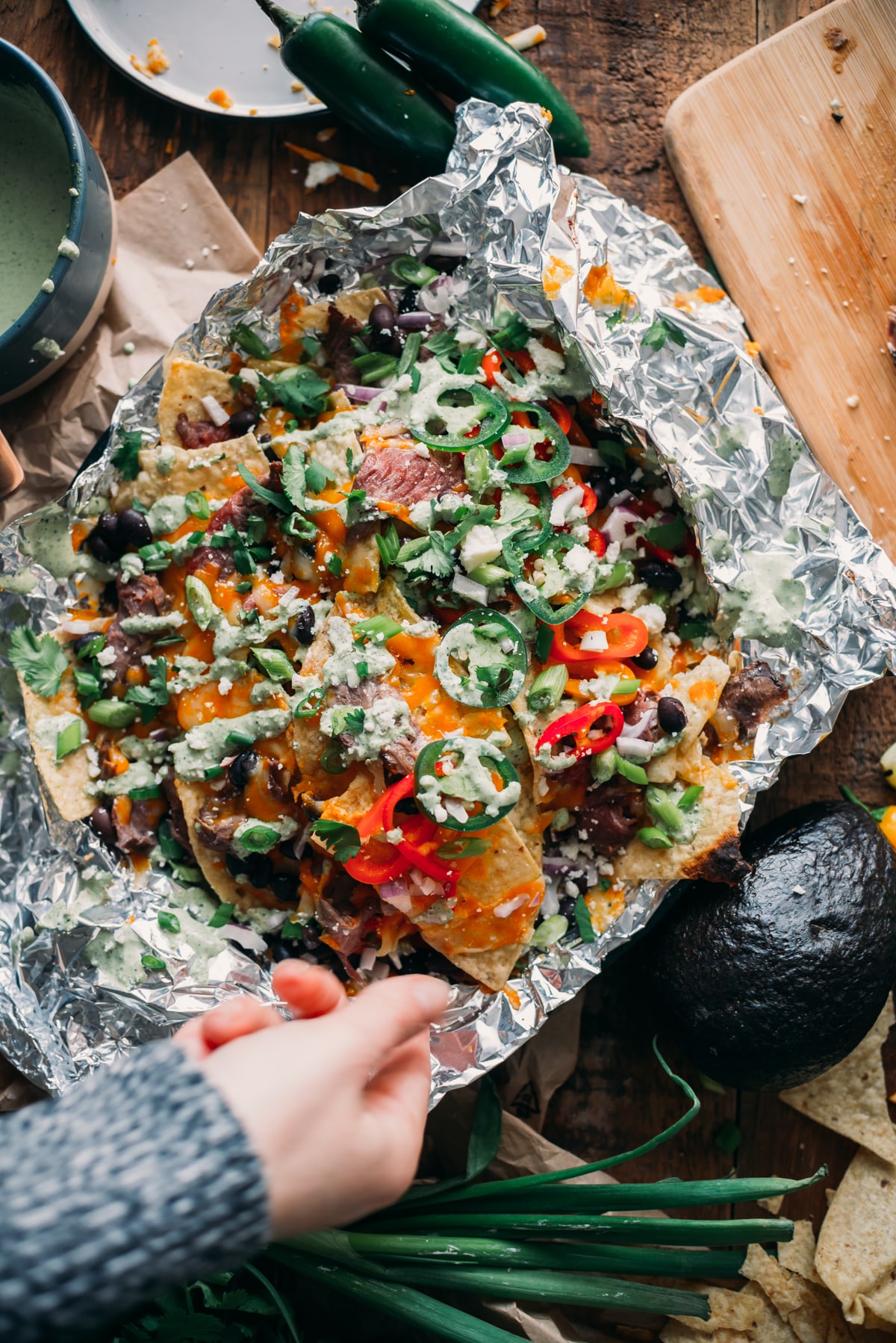 Overhead shot of nachos in foil covered in delicious toppings. 