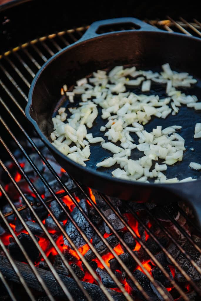 Sauté White Onions and garlic in a cast iron skillet over charcoal 