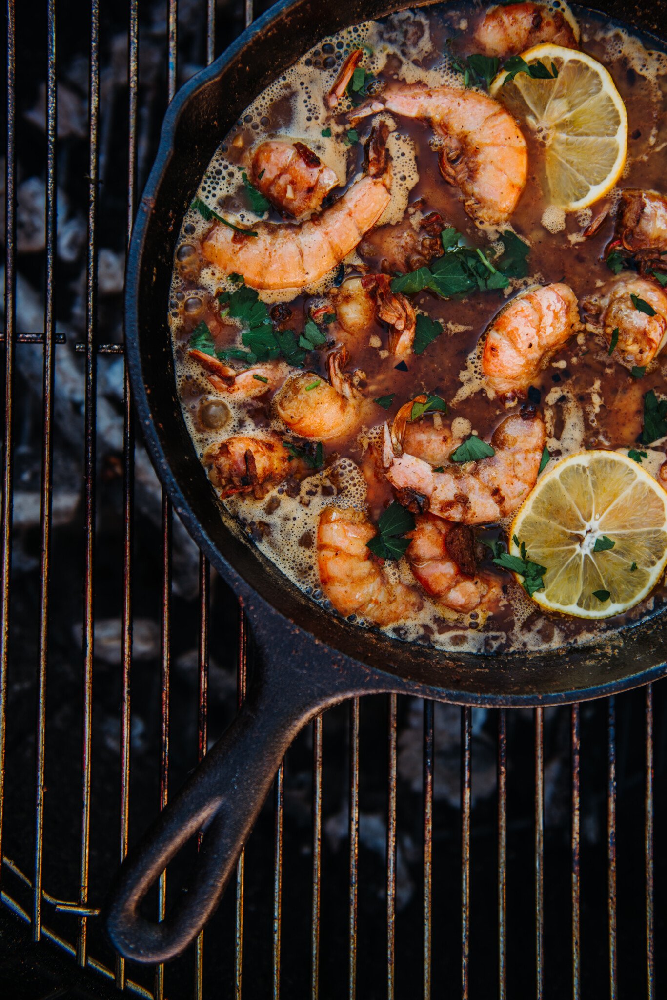Cast iron skillet of new orleans shrimp on grill.