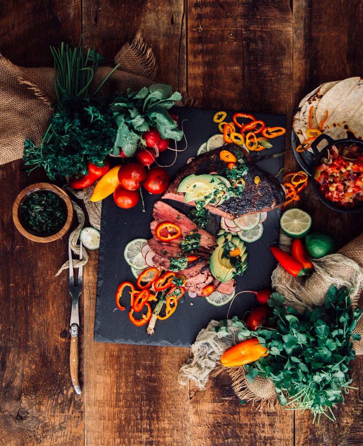 Grilled tri tip, sliced and drizzled with chimichurri over colorful sliced veggies.