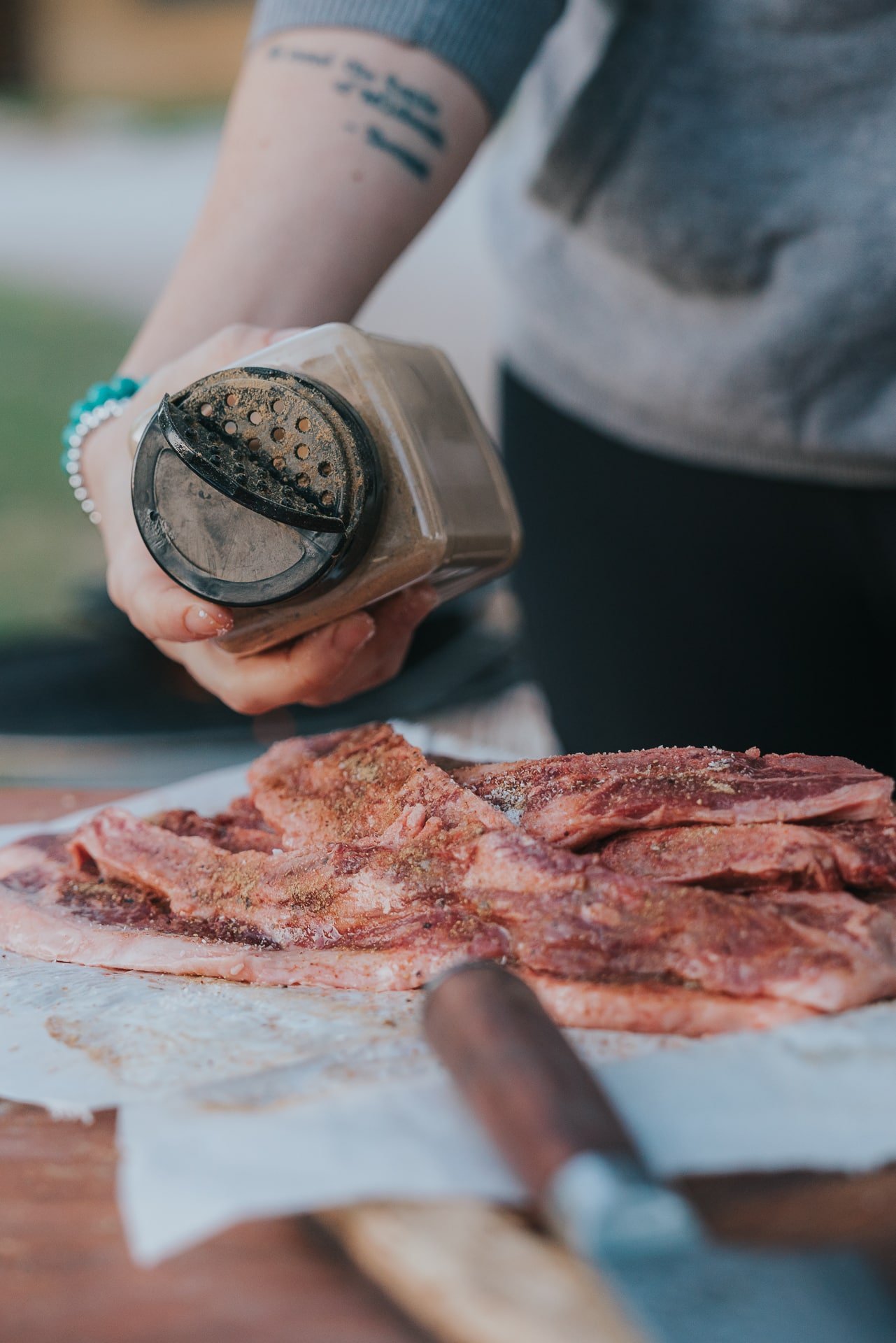 Hand shaking umami powder over flanked style short ribs. 